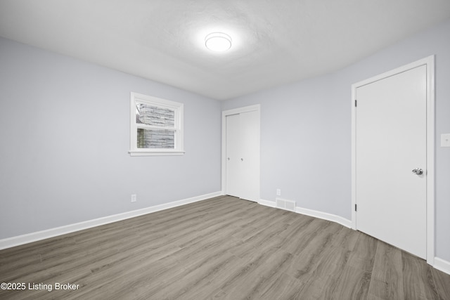 spare room with visible vents, baseboards, and wood finished floors