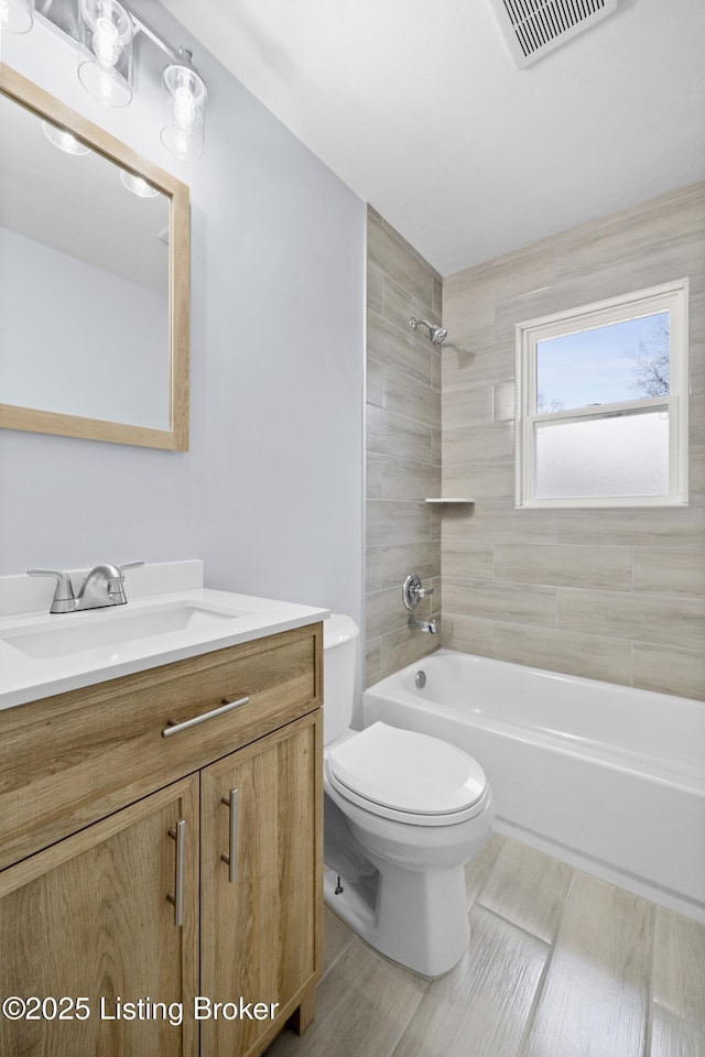 full bathroom featuring shower / bath combination, visible vents, toilet, vanity, and wood finished floors