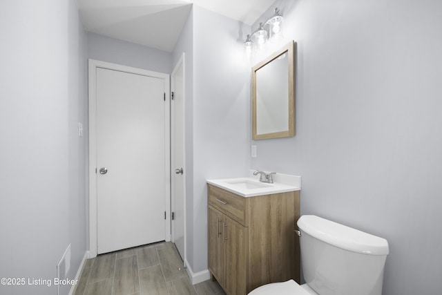 bathroom with baseboards, vanity, and toilet