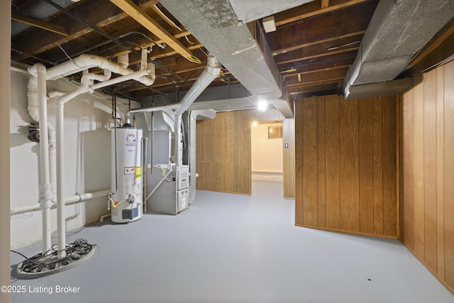 unfinished below grade area featuring water heater, wood walls, and heating unit