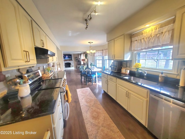 kitchen featuring stainless steel appliances, an inviting chandelier, dark wood-type flooring, a sink, and under cabinet range hood