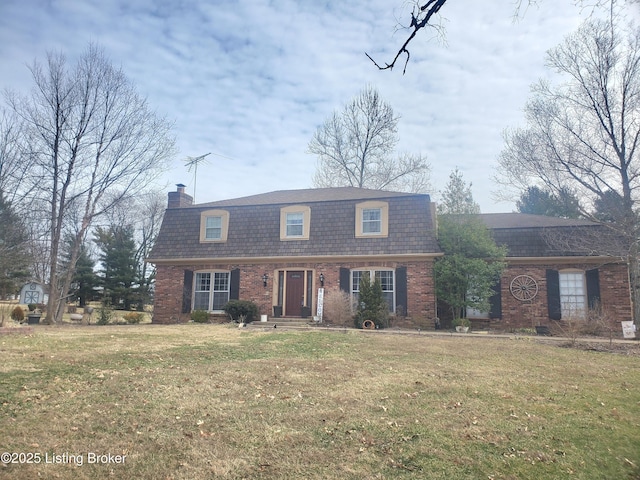 dutch colonial with roof with shingles, a front yard, a chimney, and brick siding