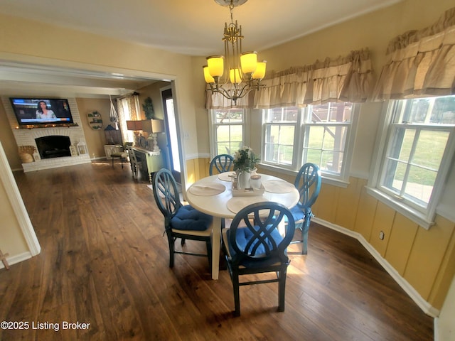 dining room with a chandelier, dark wood-style flooring, and a fireplace