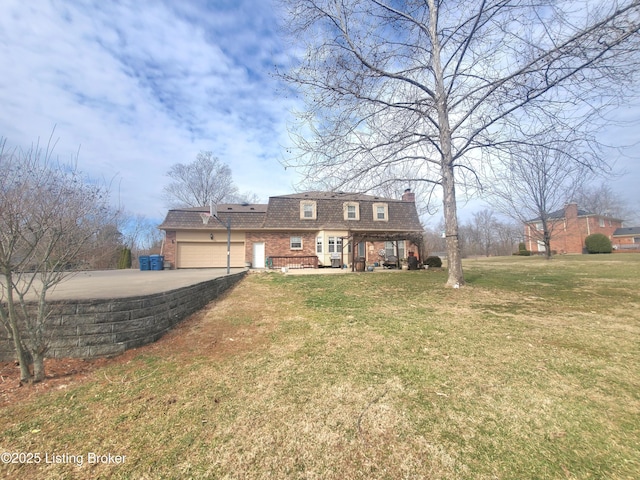 colonial inspired home with brick siding, mansard roof, a garage, driveway, and a front lawn