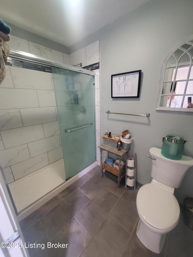 bathroom featuring tile patterned flooring, a shower stall, and toilet