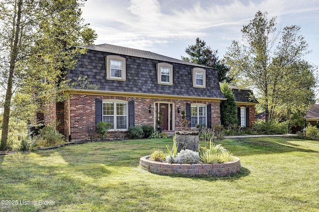 dutch colonial featuring brick siding, mansard roof, a front lawn, and roof with shingles