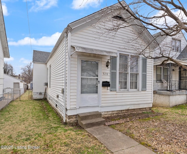 shotgun-style home featuring roof with shingles, fence, and a front yard