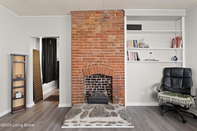 sitting room with a drop ceiling, a fireplace, baseboards, and wood finished floors