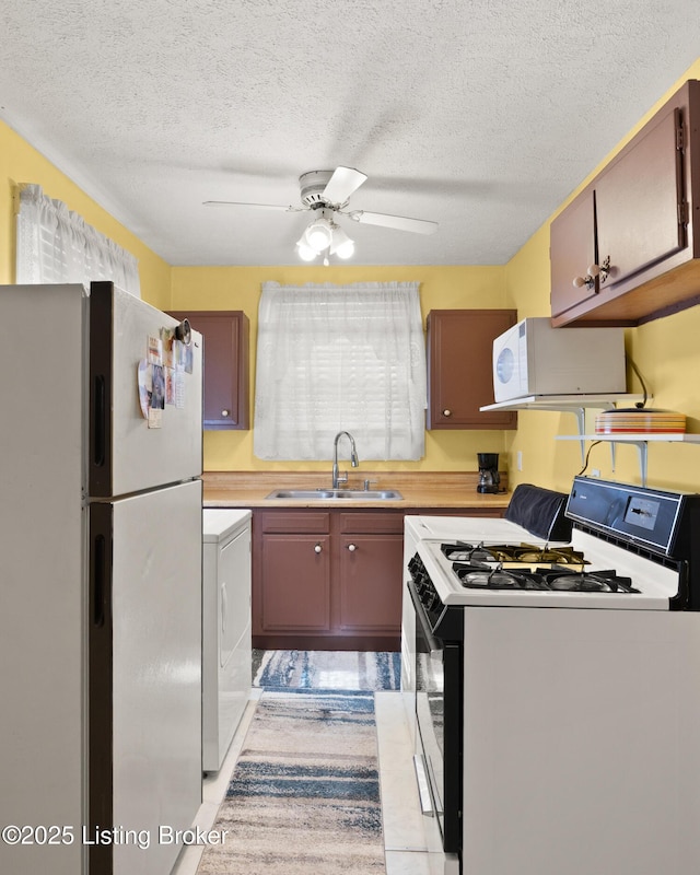 kitchen featuring light countertops, white appliances, a sink, and washer / dryer