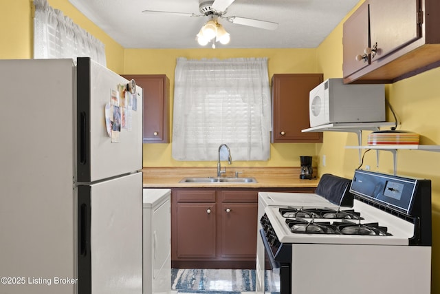 kitchen with light countertops, white appliances, a sink, and washer / dryer