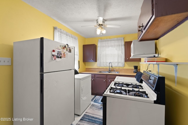 kitchen with white appliances, washer / dryer, a ceiling fan, light countertops, and a sink