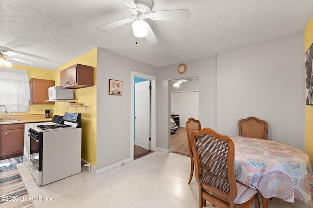 kitchen featuring a ceiling fan, a sink, white microwave, and gas range oven