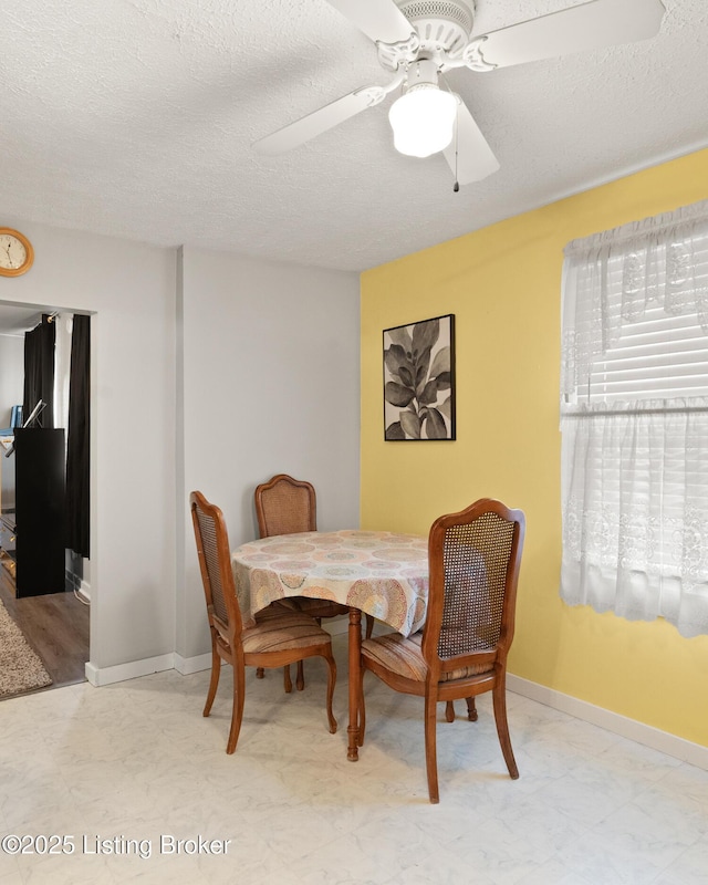 dining area with a ceiling fan, baseboards, and a textured ceiling