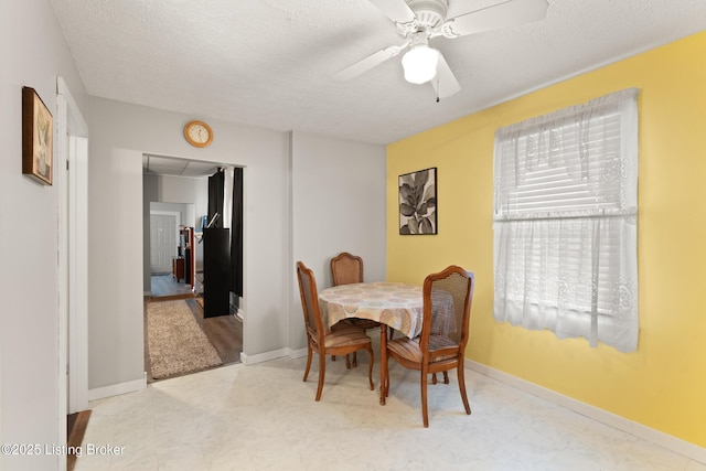 dining space with a ceiling fan, a textured ceiling, and baseboards