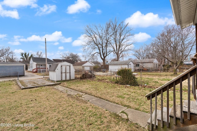 view of yard featuring an outbuilding, a shed, fence private yard, and a residential view