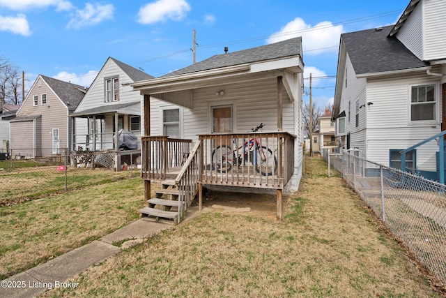 back of property with a deck, a lawn, and a fenced backyard