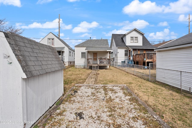 rear view of property featuring a yard, an outdoor structure, and a fenced backyard