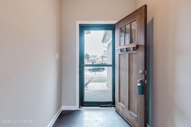 doorway to outside with baseboards and wood finished floors