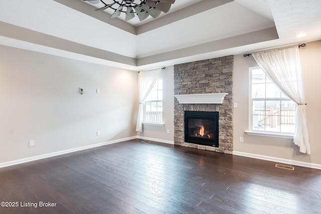 unfurnished living room with dark wood-style floors, a raised ceiling, visible vents, and baseboards