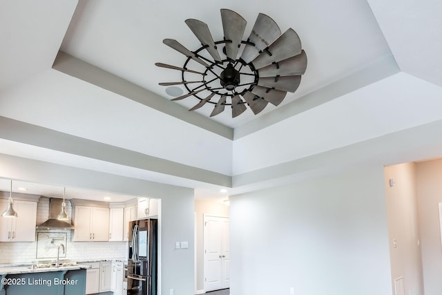 interior details featuring visible vents, a ceiling fan, wall chimney range hood, fridge with ice dispenser, and tasteful backsplash