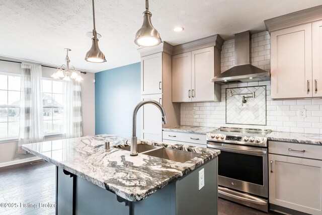 kitchen featuring decorative backsplash, light stone countertops, stainless steel electric stove, wall chimney range hood, and a sink