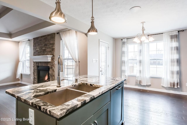 kitchen featuring open floor plan, a sink, light stone countertops, and dark wood-style floors