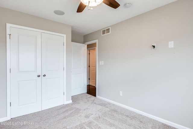 unfurnished bedroom with carpet floors, a closet, visible vents, a ceiling fan, and baseboards