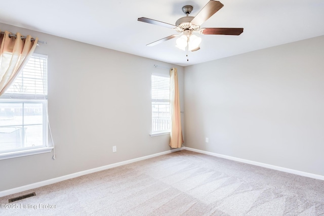 carpeted empty room featuring visible vents, ceiling fan, and baseboards