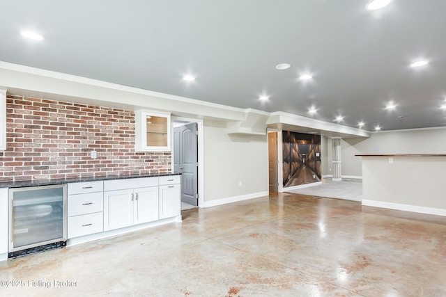 kitchen with a barn door, beverage cooler, concrete floors, white cabinetry, and baseboards