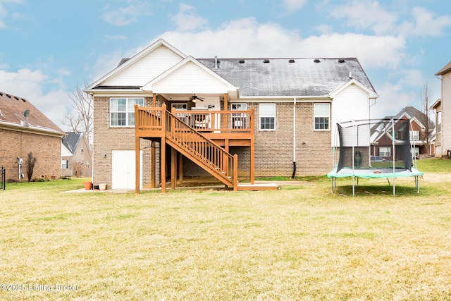 rear view of house with a deck, brick siding, a trampoline, and a ceiling fan