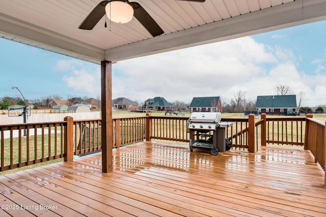 wooden terrace with fence, ceiling fan, grilling area, and a lawn