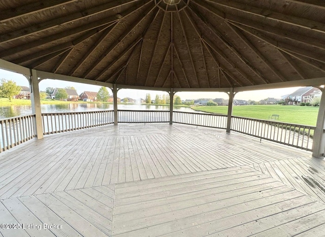 wooden terrace with a water view, a lawn, and a gazebo