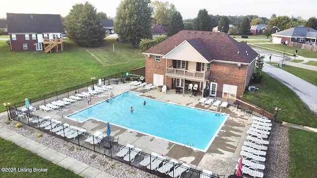 community pool featuring a lawn, a patio area, and fence