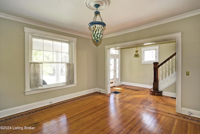 foyer featuring hardwood / wood-style flooring, stairs, baseboards, and crown molding