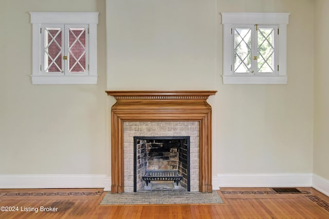 room details with baseboards, a tiled fireplace, and wood finished floors