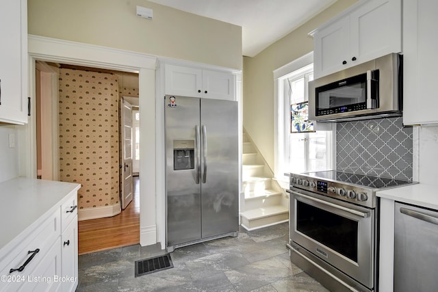 kitchen featuring visible vents, appliances with stainless steel finishes, light countertops, white cabinetry, and backsplash