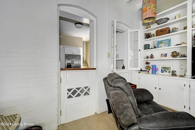 living room with light carpet and brick wall