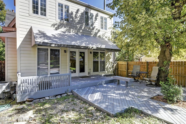 rear view of house with french doors, fence, and a wooden deck