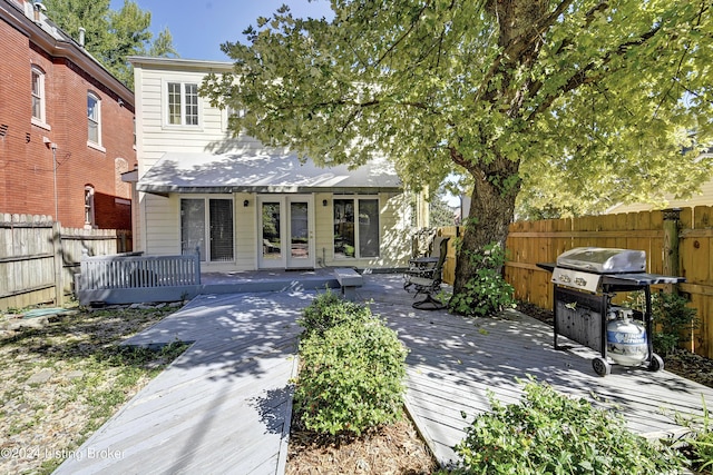 exterior space featuring fence private yard, a wooden deck, and french doors