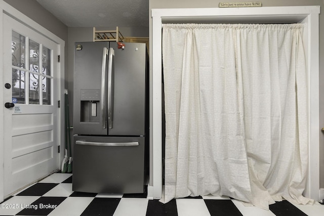 kitchen featuring a textured ceiling, stainless steel fridge with ice dispenser, and tile patterned floors