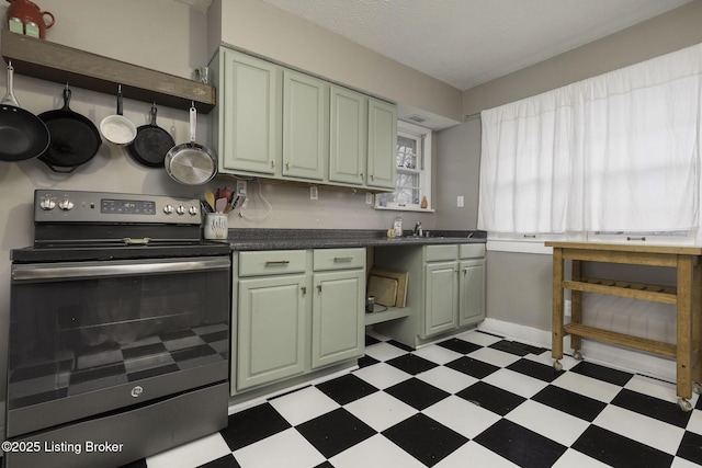 kitchen featuring stainless steel electric range oven, light floors, dark countertops, and green cabinetry