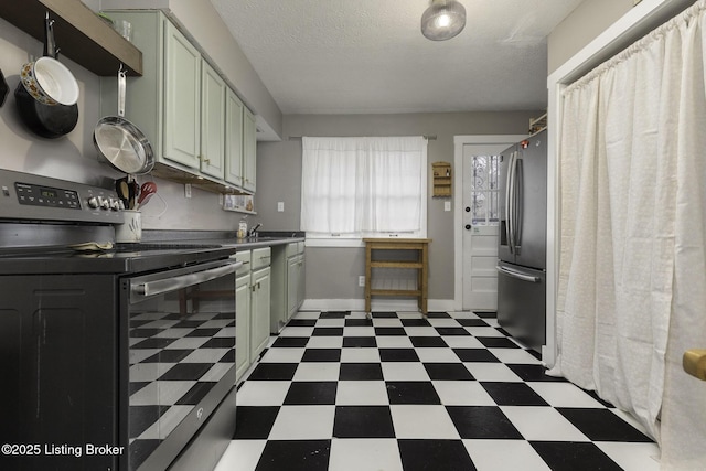 kitchen with baseboards, tile patterned floors, stainless steel appliances, a textured ceiling, and a sink