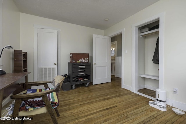 home office with a textured ceiling, visible vents, and wood finished floors