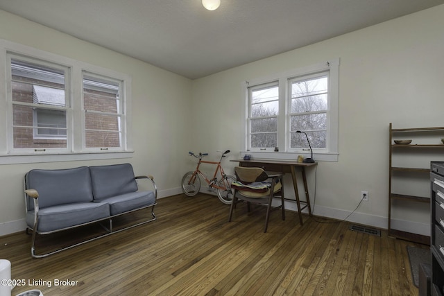 office area with baseboards, wood-type flooring, visible vents, and a healthy amount of sunlight