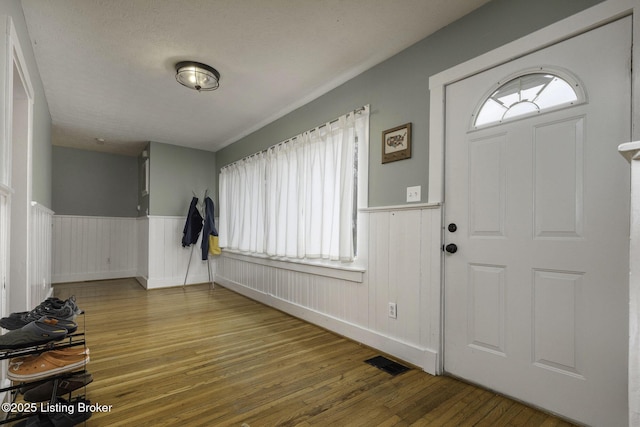 entryway with a wainscoted wall, plenty of natural light, visible vents, and wood finished floors