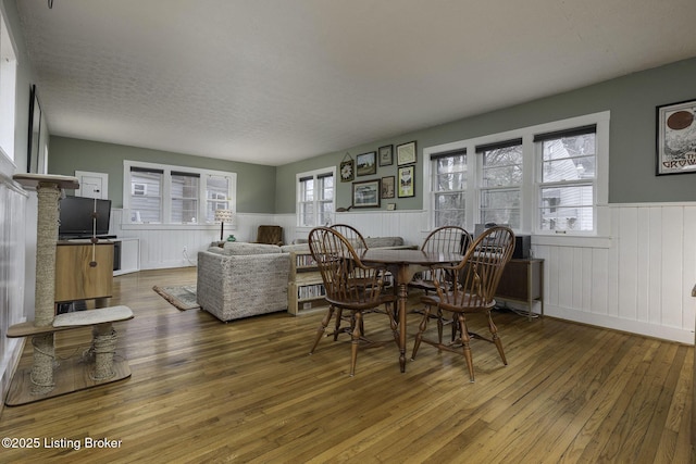 dining room featuring a wainscoted wall, hardwood / wood-style floors, and a textured ceiling