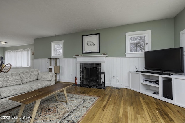 living area with a wealth of natural light, a wainscoted wall, and hardwood / wood-style floors