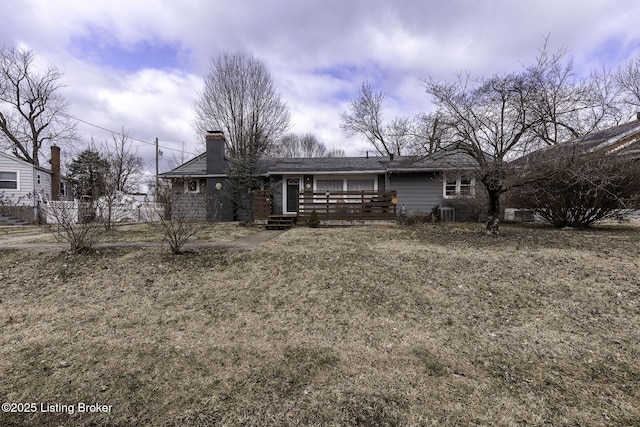 view of front of house with a front lawn, a chimney, and fence