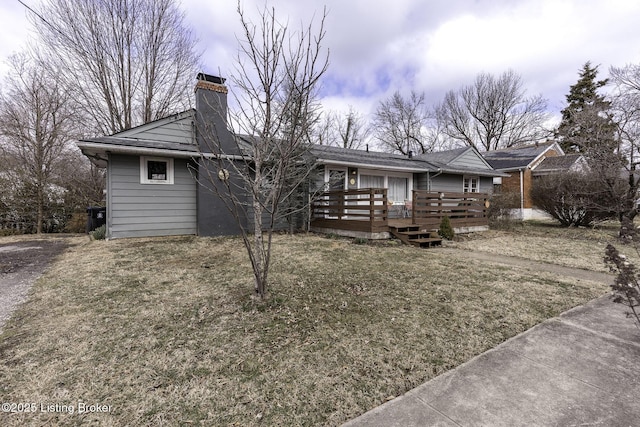 ranch-style home with a chimney, a front lawn, and a wooden deck