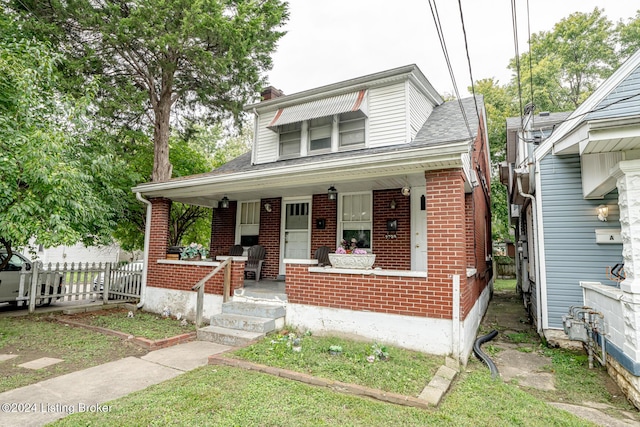 bungalow-style home featuring a chimney, roof with shingles, fence, a porch, and brick siding